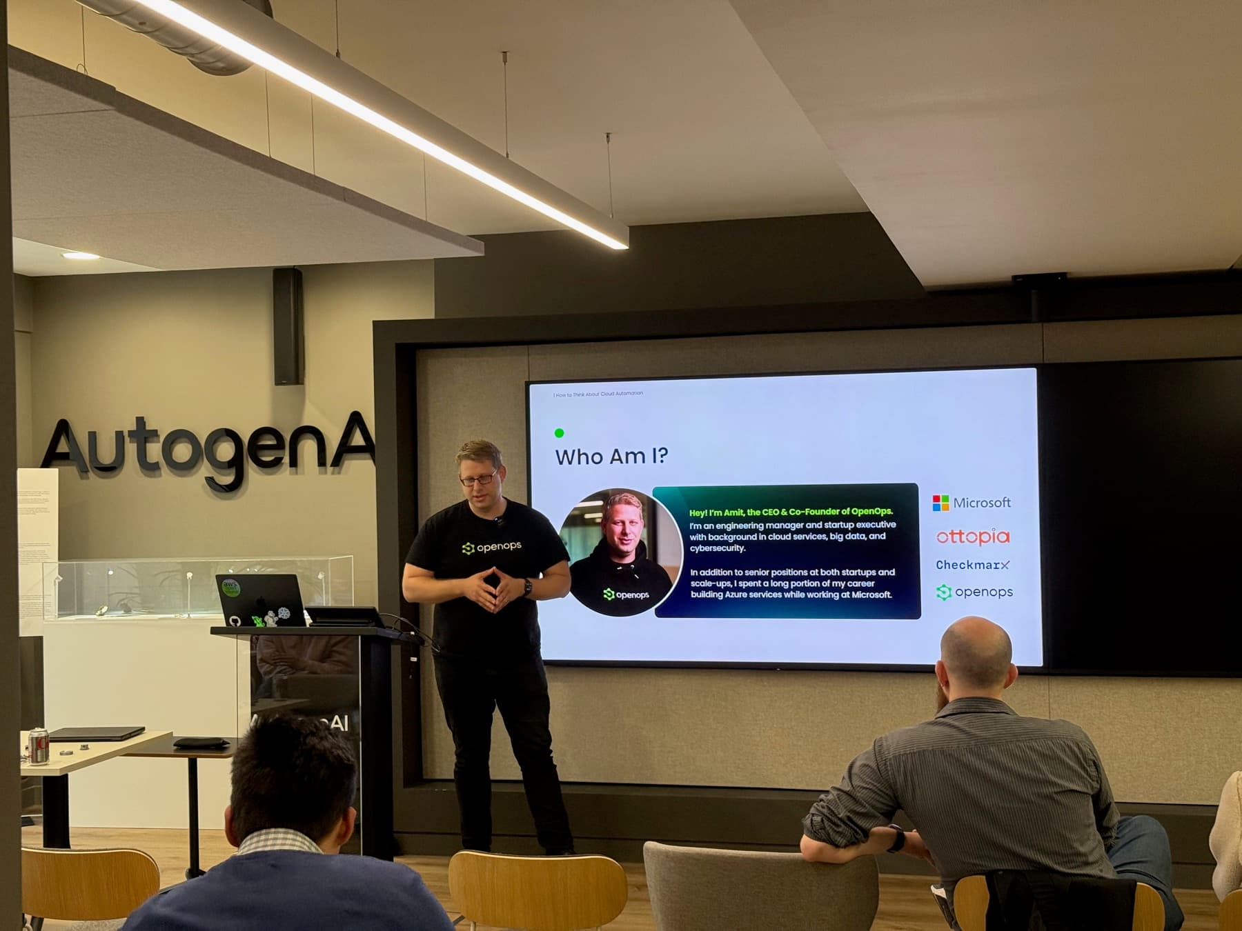 An OpenOps presentation in front of the AutogenAI sign
