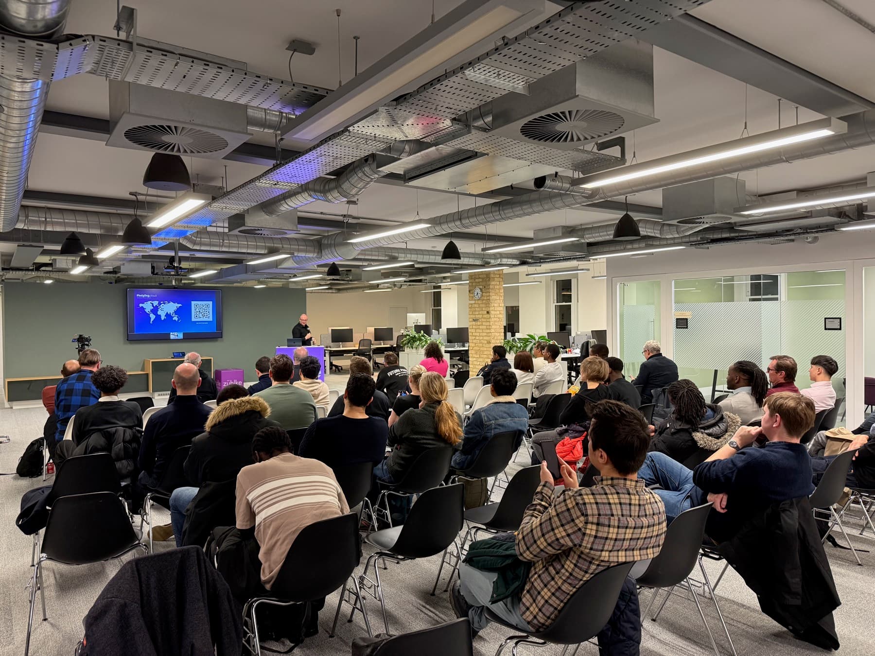 A busy audience during a talk in a large open-plan space