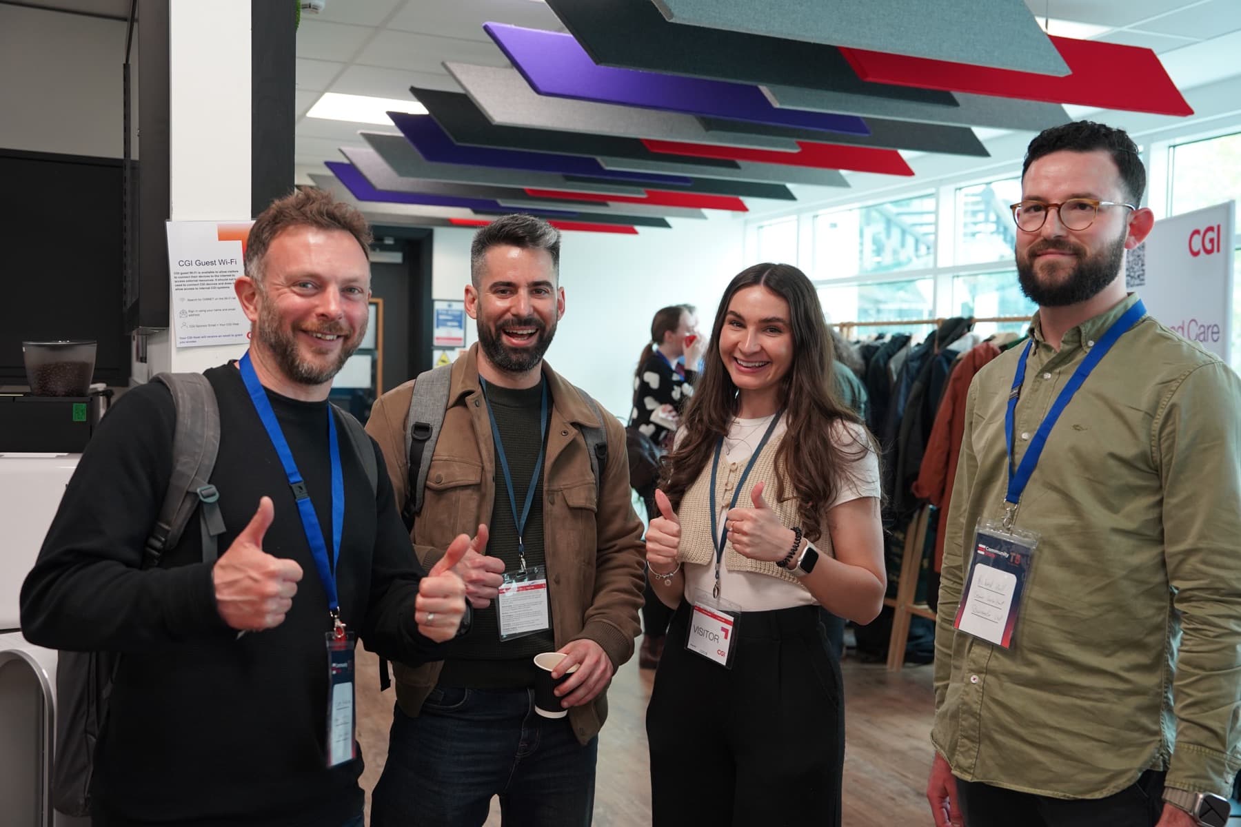 Four attendees giving a thumbs up at the conference