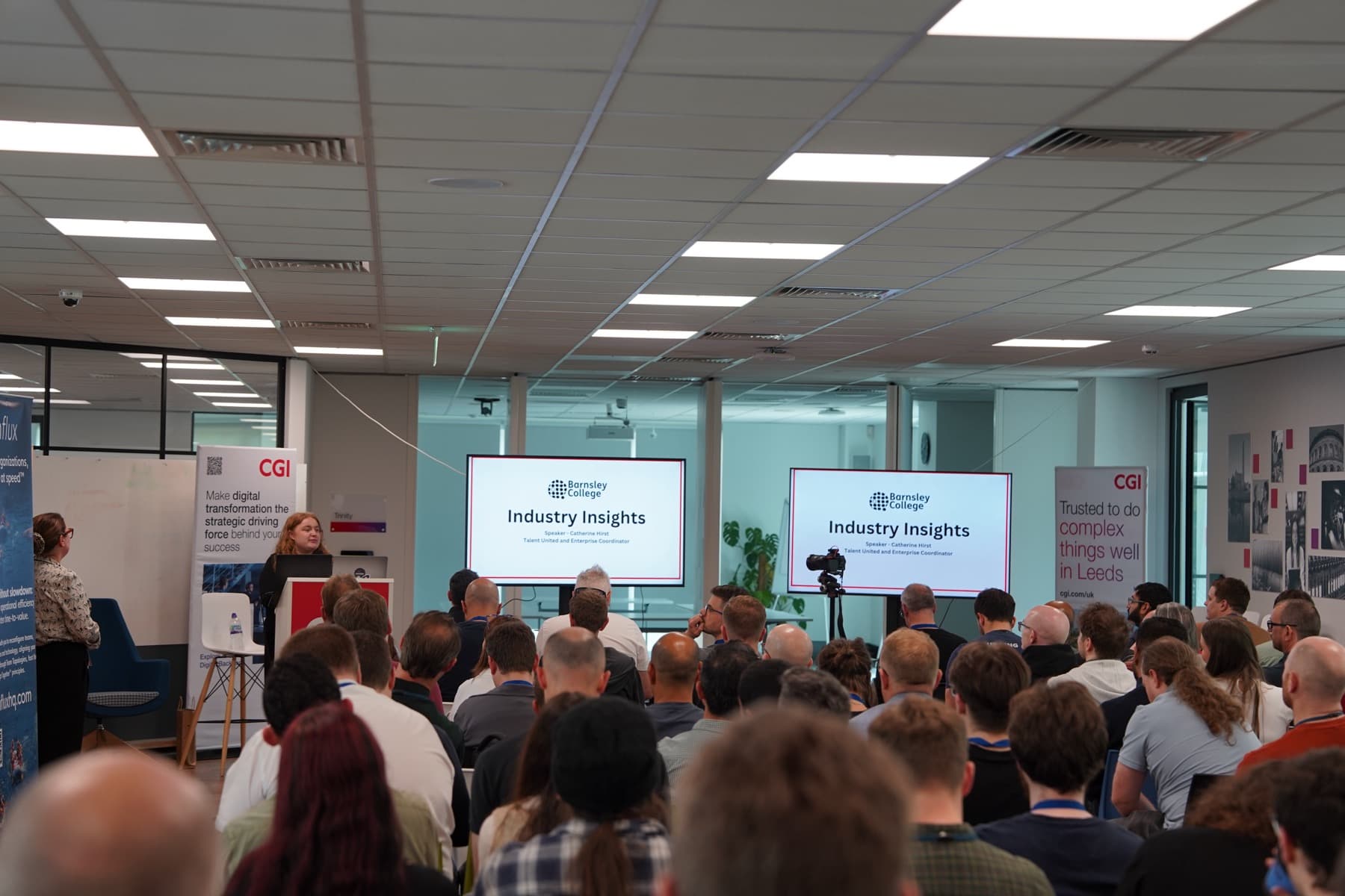 A full conference room with talks on two screens
