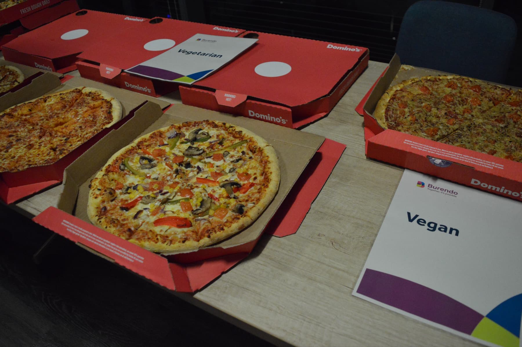 Pizza boxes laid out for attendees, with vegan options labelled